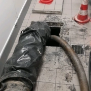 Nettoyage de canalisation avec tuyau et cônes de signalisation.