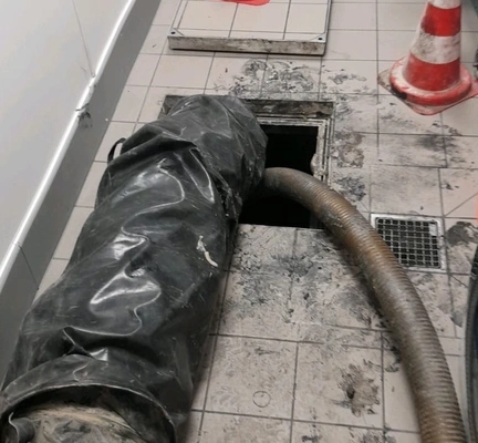 Nettoyage de canalisation avec tuyau et cônes de signalisation.
