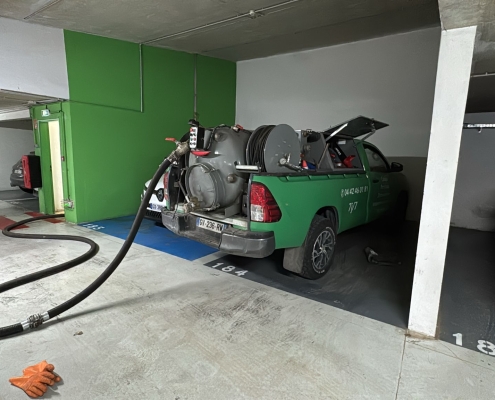 pompage fosse ascenseur pendant inondation Camion de maintenance stationné dans un parking souterrain avec tuyau aspirant