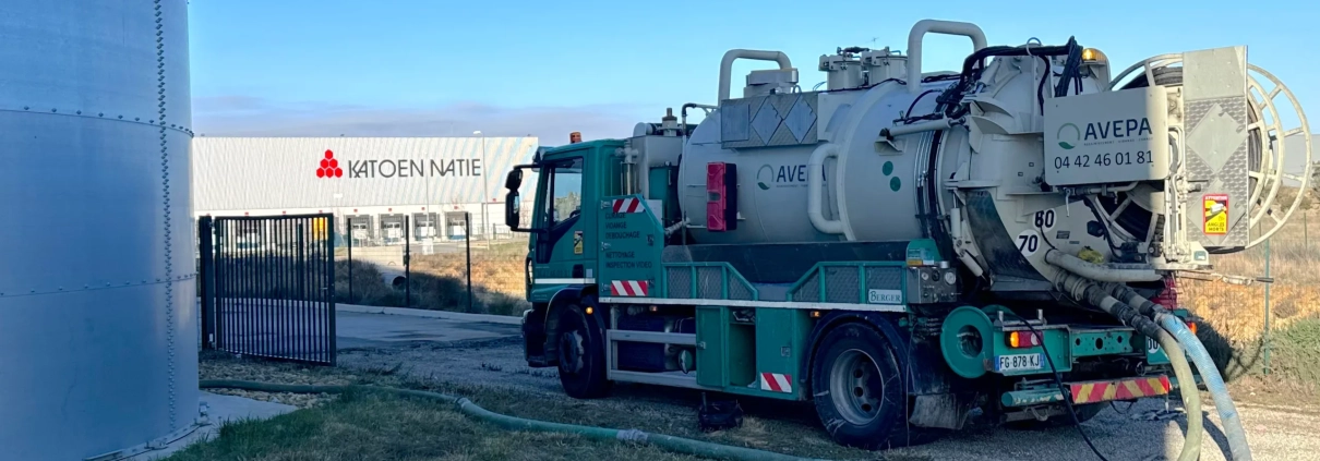 Camion de nettoyage industriel près d'un entrepôt.