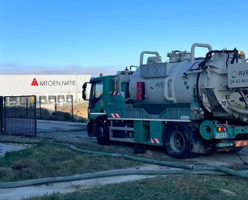 Camion de nettoyage industriel près d'un entrepôt.